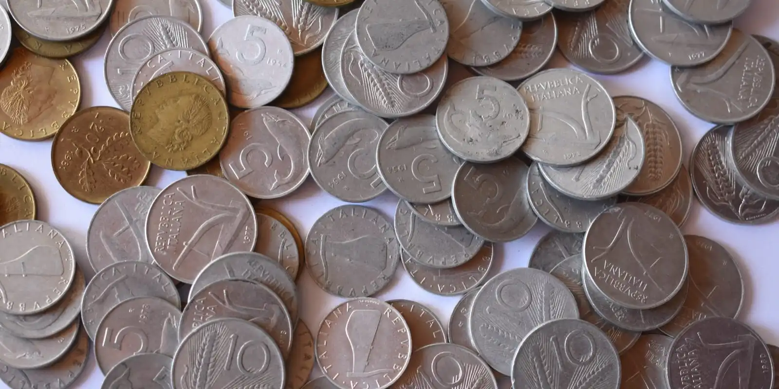 A pile of old silver and brass coins of different sizes, seen from above.